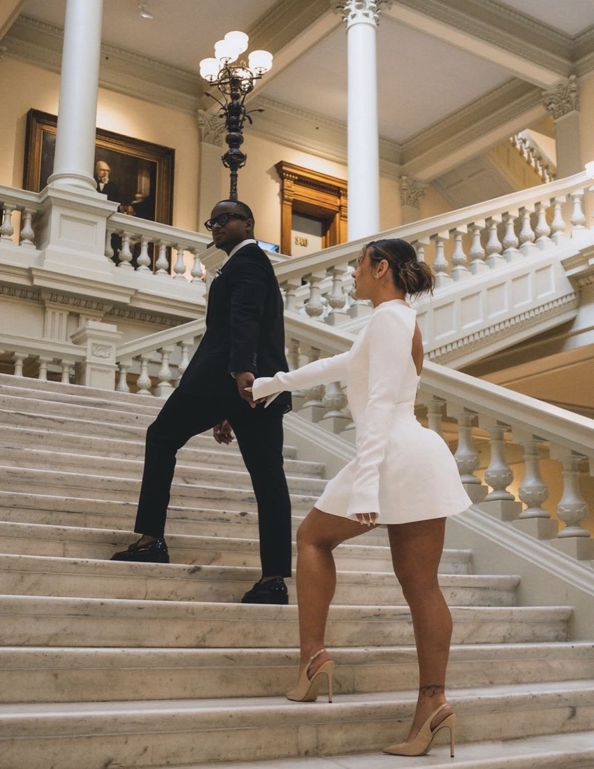 A couple holding hands, walking up a marble staircase